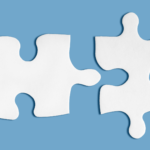 Photo of two white puzzle pieces nearly touching on a blue background