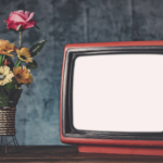 Photo of antique TV next to a vase of flowers