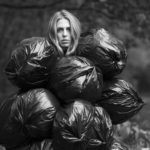 Woman staring at the camera with six black trash bags covering her body