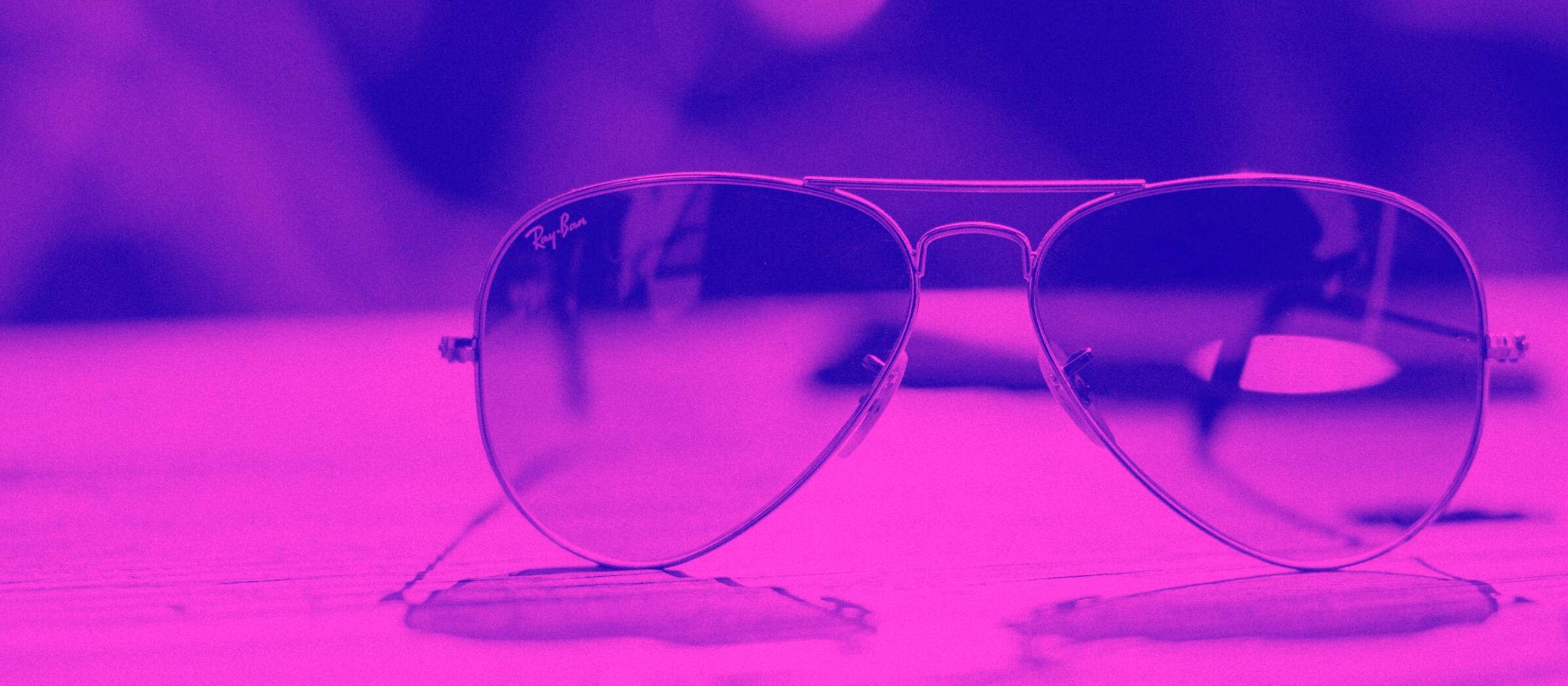 Photo of aviator sunglasses through a bright purple filter