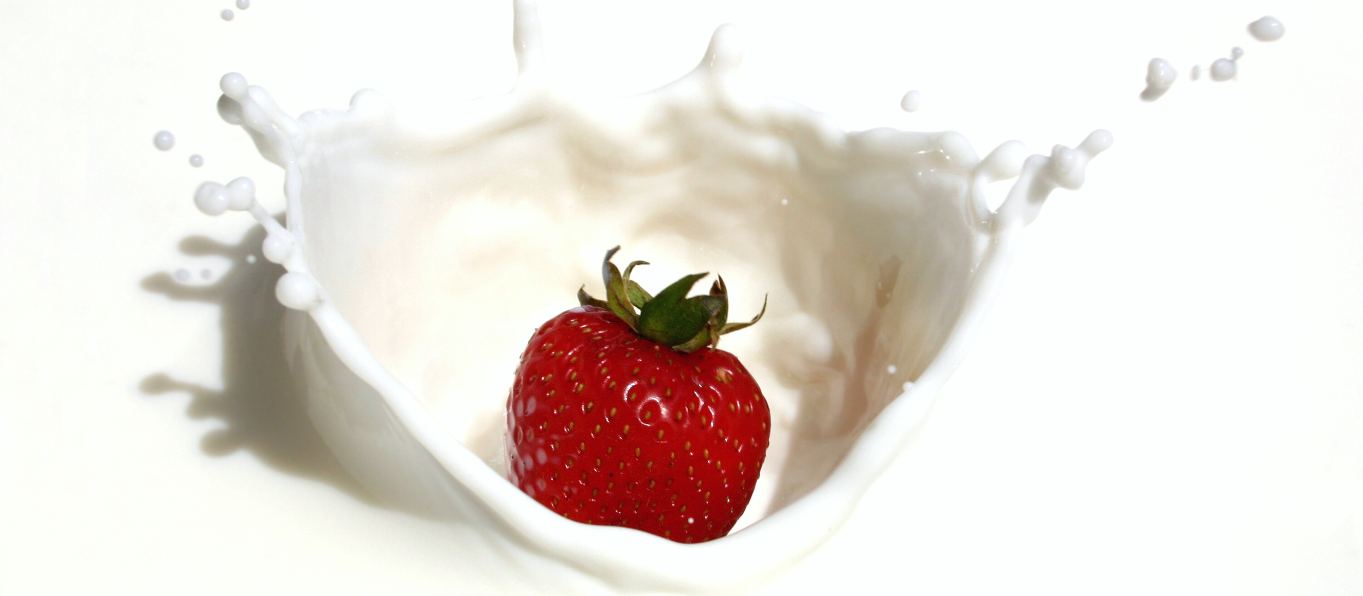 Photo of a strawberry dropping into milk